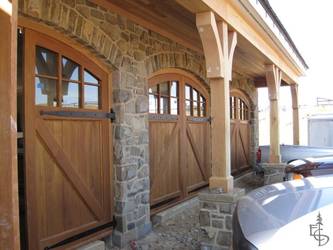 Arched carriage doors grace a beautiful stone carriage house.